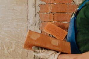 Man picking up bricks after building a brick wall